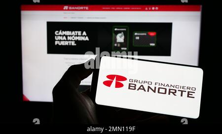 Person, die ein Handy mit dem Logo des mexikanischen Bankunternehmens Grupo Financiero Banorte auf dem Bildschirm vor der Webseite hält. Konzentrieren Sie sich auf das Display des Telefons. Stockfoto