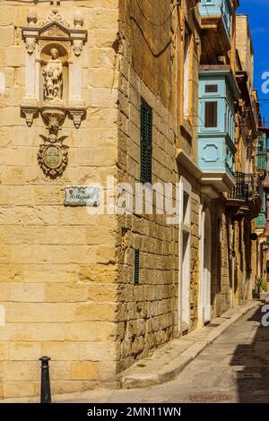 Birgu, Malta - 10. April 2012: Blick auf eine Allee in der Altstadt mit typischen geschnitzten Figuren in Birgu (Vittoriosa), Malta Stockfoto