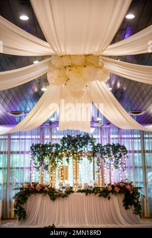 Hochzeitspaar wunderschön dekorierter Tisch in einem Restaurant mit Lichtern, grünen Pflanzen und Blumen. Hochwertiges Foto Stockfoto