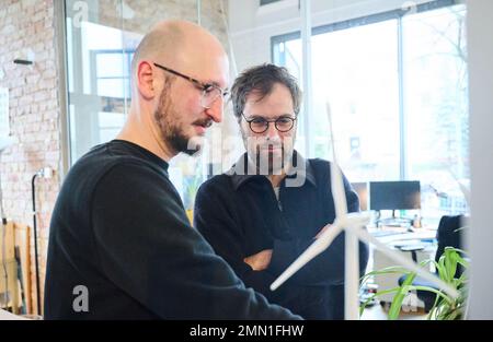 Berlin, Deutschland. 27. Januar 2023. Daniel Deppe (l), Projektingenieur für Windenergie und Umweltplaner, und Elias Brunken, Projektingenieur für Windenergie und erneuerbare Energien, untersuchen im Büro des Unternehmens Teut Windprojekte Windturbinenmodelle. (Dpa 'Turbo für LNG, Brems für Wind? Warum die Energiewende lahm ist') Kredit: Annette Riedl/dpa/Alamy Live News Stockfoto