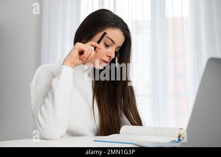 Eine müde und gestresste Frau hat ein Problem mit einem Geschäft. Freiberuflicher Mitarbeiter arbeitet sorgfältig an dem Projekt. Stockfoto