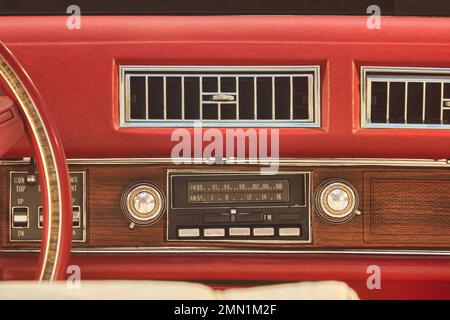 Altes Autoradio in einem roten klassischen amerikanischen Auto mit Armaturentafel aus Chrom und Holz Stockfoto