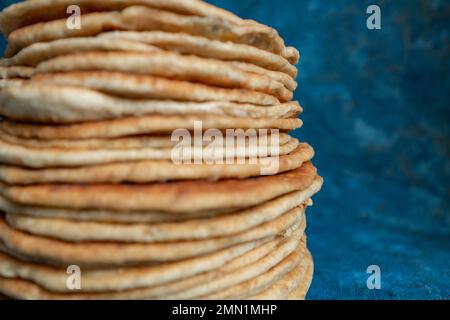 Fladenbrot Lavash, Chapati, Naan, ein Haufen Tortilla auf blauem Hintergrund hausgemachtes Fladenbrot gestapelt. Stockfoto