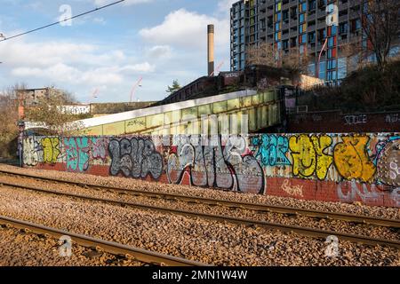 Yorkshire, Vereinigtes Königreich – 21. Dezember 2020: Eine Mauer aus Graffiti neben leeren Straßenbahnschienen vor Park Hill Flats an einem hellen Dezembertag in Sheffield, Vereinigtes Königreich Stockfoto