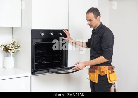 Nicht mit der Reparatur verzögern. Nahaufnahme der reparateur Backofen Prüfung mit einem Schraubendreher in der Küche im Koffer Stockfoto