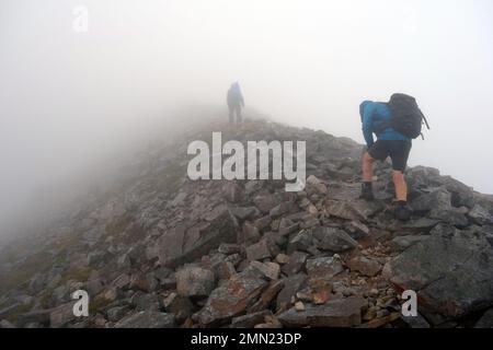 Two Men Walking in Low Cloud on the Rocky Ridge zum Gipfel des Scottish Mountain Corbett „Ben Damph“ in den schottischen Highlands, Schottland, Großbritannien. Stockfoto