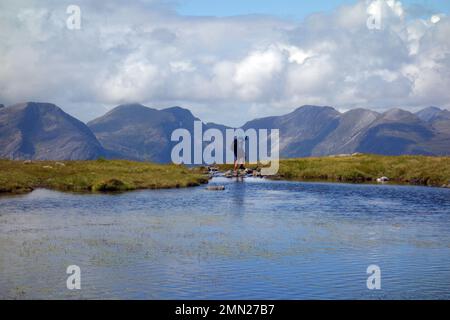 Mann mit den „Coulin Hills“ Fuar Tholl, Sgurr Ruadh & Beinn Liath Mhor von Loch Sgurr na Feartaig in den schottischen Highlands, Schottland, Großbritannien. Stockfoto