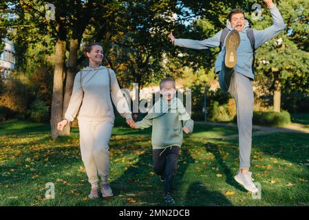 Eine familienmutter und 2 Söhne haben Spaß, Rennen im Park und springen. Söhne, Kinder, mom, Lauf, Spiel, Freuen Sie sich, genießen Sie die Natur im Sommer. Familie Stockfoto