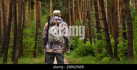 Rückansicht eines Jägers mit Rucksack und Waffe Stockfoto
