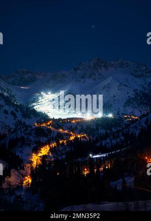 Landschaft der glühenden Straße von Medeu Schlittschuhlaufen zum Shymbulak Skigebiet in den Tian Shan Bergen bei Nacht in Almaty City, Kasachstan Stockfoto