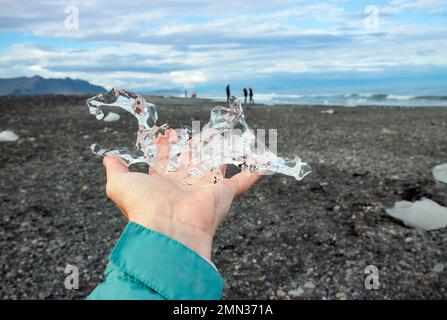 Nahaufnahme einer Touristenfrau, die im Sommer Gletschereis auf dem Island Place namens Diamond Beach hält. Stockfoto