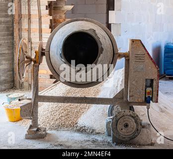 Der Arbeiter benutzt einen Beton aus einem Betonmischer Stockfoto