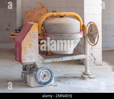 Der Arbeiter benutzt einen Beton aus einem Betonmischer Stockfoto