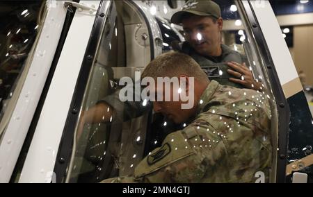 SPC. Hunter Wolfe (Front), ein Air Defense Battle Management System Operator mit der Air Defense Artillery 1-265., lernt von Stephen Kersey, einem Piloten beim Osceola Sheriff's Department (Back), über die Bedeutung der Helikopterunterstützung während eines Hurricanes und zeigt ihm die Kabine. Das ist als Vorbereitung für den Hurrikan Ian in Kissimmee, Florida. 28. September 2022. Stockfoto