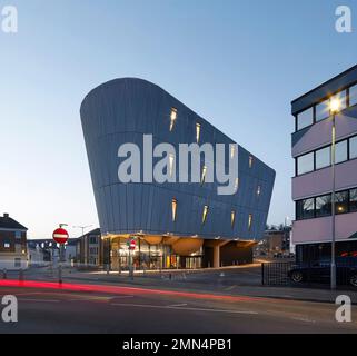 Blick in die Abenddämmerung auf der anderen Straßenseite in Richtung Skatepark mit Aluminiumgitterverkleidung. F51 Skatepark, Folkestone, Vereinigtes Königreich. Architekt: Hollaway Studio, 2022. Stockfoto