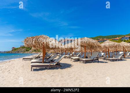 Strohschirme und Sonnenliegen am Meer. Stockfoto