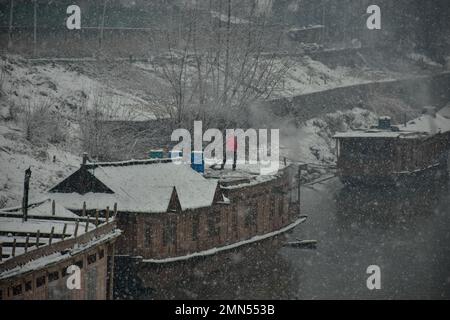 Srinagar, Indien. 30. Januar 2023. Ein Mann räumt während des Schneefalls in Srinagar Schnee von seinem Hausboot. Das Kaschmir-Tal war von der Außenwelt abgeschnitten, alle Flüge zum und vom Flughafen Srinagar wurden gestrichen und die Nationalautobahn wurde wegen starkem Schneefall am Montagmorgen gesperrt. Kredit: SOPA Images Limited/Alamy Live News Stockfoto