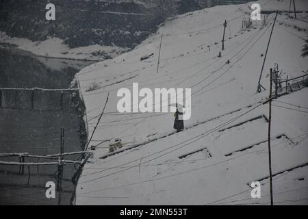 Srinagar, Indien. 30. Januar 2023. Eine Frau hält einen Regenschirm, während sie während des Schneefalls in Srinagar nach unten geht. Das Kaschmir-Tal war von der Außenwelt abgeschnitten, alle Flüge zum und vom Flughafen Srinagar wurden gestrichen und die Nationalautobahn wurde wegen starkem Schneefall am Montagmorgen gesperrt. Kredit: SOPA Images Limited/Alamy Live News Stockfoto