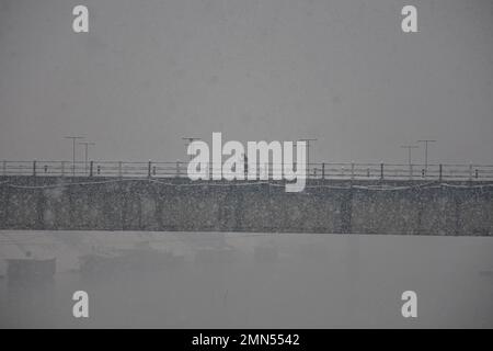 Srinagar, Indien. 30. Januar 2023. Ein Mann geht während des Schneefalls in Srinagar entlang der schneebedeckten Brücke. Das Kaschmir-Tal war von der Außenwelt abgeschnitten, alle Flüge zum und vom Flughafen Srinagar wurden gestrichen und die Nationalautobahn wurde wegen starkem Schneefall am Montagmorgen gesperrt. Kredit: SOPA Images Limited/Alamy Live News Stockfoto