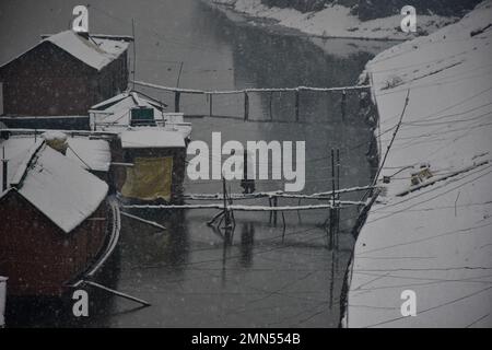 Srinagar, Indien. 30. Januar 2023. Eine Frau geht während des Schneefalls in Srinagar auf ihr Hausboot zu. Das Kaschmir-Tal war von der Außenwelt abgeschnitten, alle Flüge zum und vom Flughafen Srinagar wurden gestrichen und die Nationalautobahn wurde wegen starkem Schneefall am Montagmorgen gesperrt. Kredit: SOPA Images Limited/Alamy Live News Stockfoto