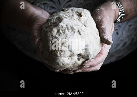 Großmutterhände mit einem Ball Brotteig Stockfoto