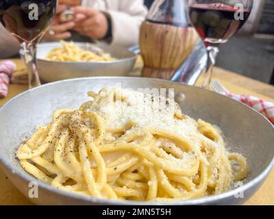 italienisches Essen, leckere handgemachte Pasta mit Käse auf dem Tisch. Typische und traditionelle italienische Spaghetti und lokale Rotweine auf dem Tisch in Rom, IT Stockfoto