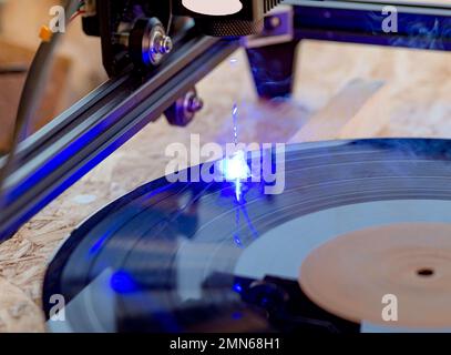Lasergravierer, Laserverbrennung auf alten Schallplatten mit 33 U/min Stockfoto
