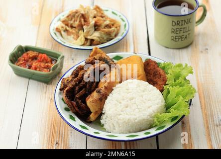 Nasi Cumi Bakar, Reis mit gegrilltem Tintenfisch, Tempeh, Tofu. Serviert mit Sambal und Kol Goreng. Beliebt als Tagesmenü in Indonesien namens Penyetan Stockfoto