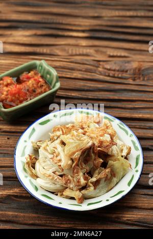 Kol Goreng oder gebratener Kohl, indonesisches Beilagenmenü für Penyetan und Pecel Lele. Serviert mit scharfem Sambal auf einem Holztisch Stockfoto