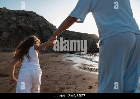 Mutterliebe. Mama umarmt ihre Töchter, küsst und spielt, zärtlich und fürsorglich. Freundliche Familie zu Hause und im Urlaub. Stockfoto