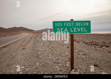 Ein Schild im Death Valley National Park zeigt an, dass die Höhe 100 Fuß unter dem Meeresspiegel liegt. Stockfoto