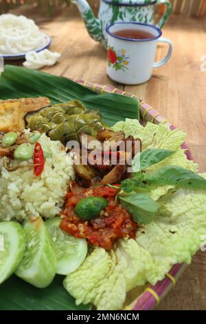 Das Nasi liwet Gericht enthält Reis, Brathähnchen, Petai, Jengkol, gebratene Sardellen, Gebratener Tofu und Gemüse Stockfoto