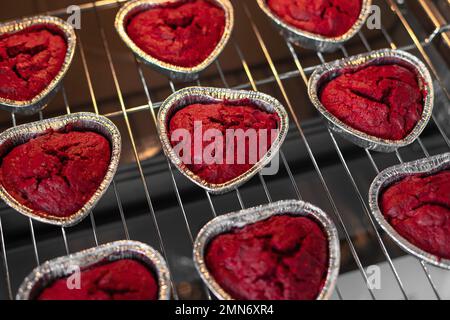 Herzförmige rote Samt-Cupcakes in einem Ofen Stockfoto
