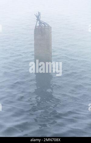 Eine malerische Betonsäule ragt aus dem Wasser Stockfoto
