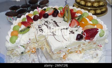 Halber Obstkuchen auf dem Tisch mit anderem Dessert zur Geburtstagsfeier Stockfoto