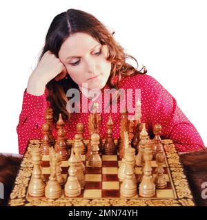 Junge Frau, die Schach spielt, während sie zu Hause am Schachbrett sitzt, Nahporträt, isoliert auf weißem Hintergrund Stockfoto