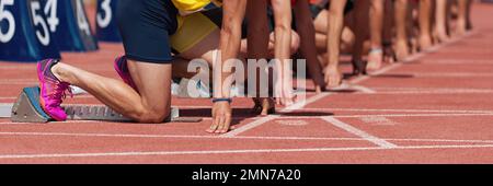 Gruppe männlicher Leichtathleten auf Startblöcken. Hände auf der Startlinie. Athleten auf der Sprint Startlinie in Leichtathletik Stockfoto