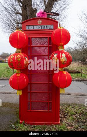 Altmodische rote Telefonzelle (Telefonkiosk), dekoriert für das chinesische Neujahr, das Jahr des Hasen, im Dorf Compton in Surrey, Großbritannien. Januar 2023 Stockfoto