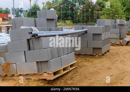 Eine Reihe von Zementblöcken, die zur Verlegung an der Wand des Hauses bereit sind, befinden sich an der Seite der Baustelle. Stockfoto