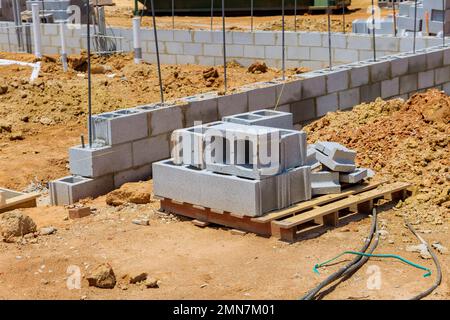 Auf der Baustelle ist zu sehen, dass die Zementblöcke gestapelt sind, sodass sie an der Wand des Hauses verlegt werden können. Stockfoto