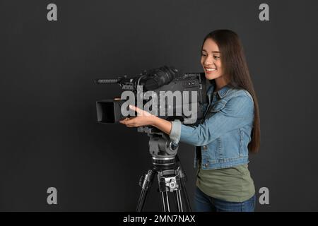 Bediener mit professioneller Videokamera auf schwarzem Hintergrund Stockfoto