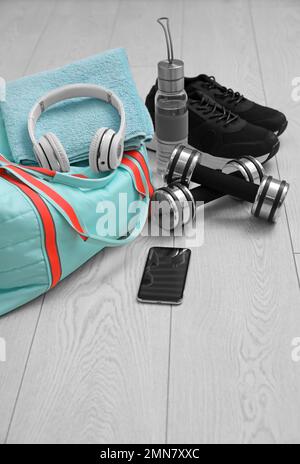Sporttasche und Fitnesszeug auf Holzboden Stockfoto