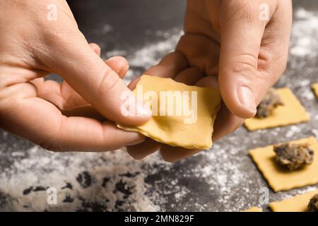 Eine Frau, die Ravioli am grauen Tisch macht, Nahaufnahme. Italienische Pasta Stockfoto