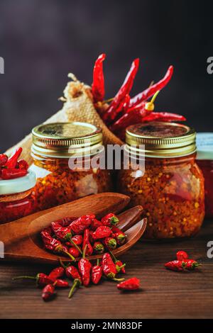 Verschiedene Arten von roten, heißen Chili-Paprika. Hausgemacht und in Glasgefäßen für Konfitüren gelagert Stockfoto