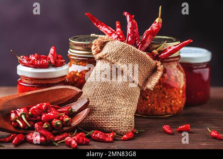 Verschiedene Arten von roten, heißen Chili-Paprika. Hausgemacht und in Glasgefäßen für Konfitüren gelagert Stockfoto