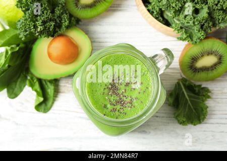 Flache Liegezusammensetzung mit Grünkohl-Smoothie auf weißem Holztisch Stockfoto