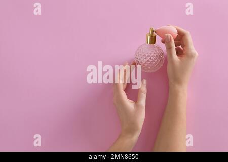 Frau mit einer Flasche Parfüm auf pinkfarbenem Hintergrund, Draufsicht. Platz für Text Stockfoto