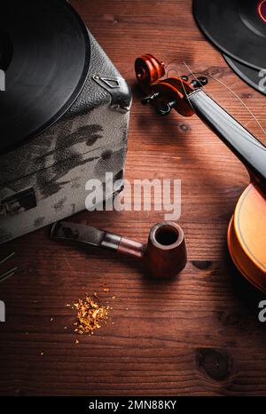 Geige, Schallplatten und Pfeife auf Holz Stockfoto