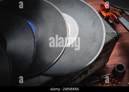 Geige, Schallplatten und Pfeife auf Holz Stockfoto