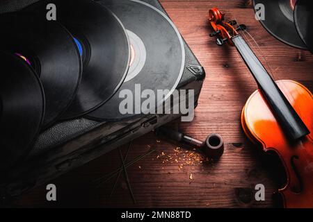 Geige, Schallplatten und Pfeife auf Holz Stockfoto